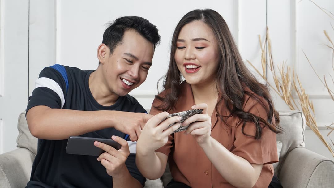 Persons laughing while playing smartphone